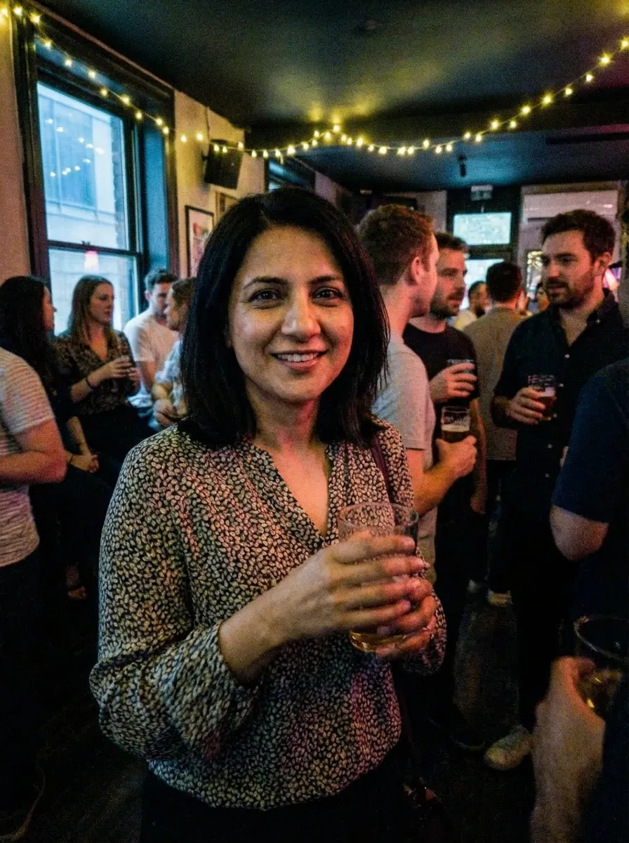 Bar photo of a woman in a patterned blouse holding a drink